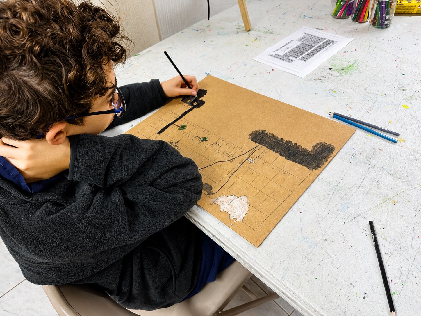 Aluno desenhando sobre papel kraft
