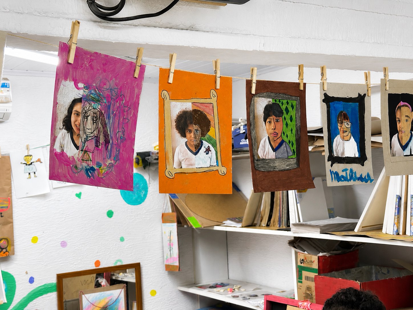 Retratos e trabalhos pendurados na sala de artes
