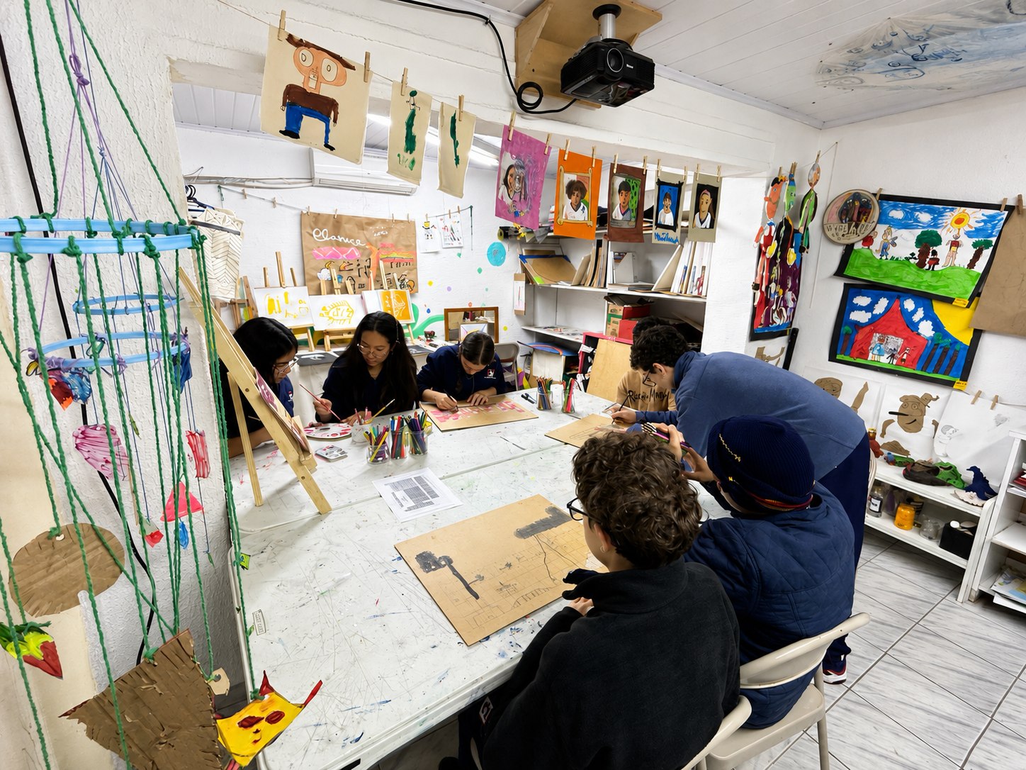 Vista ampla da sala de artes com alunos produzindo